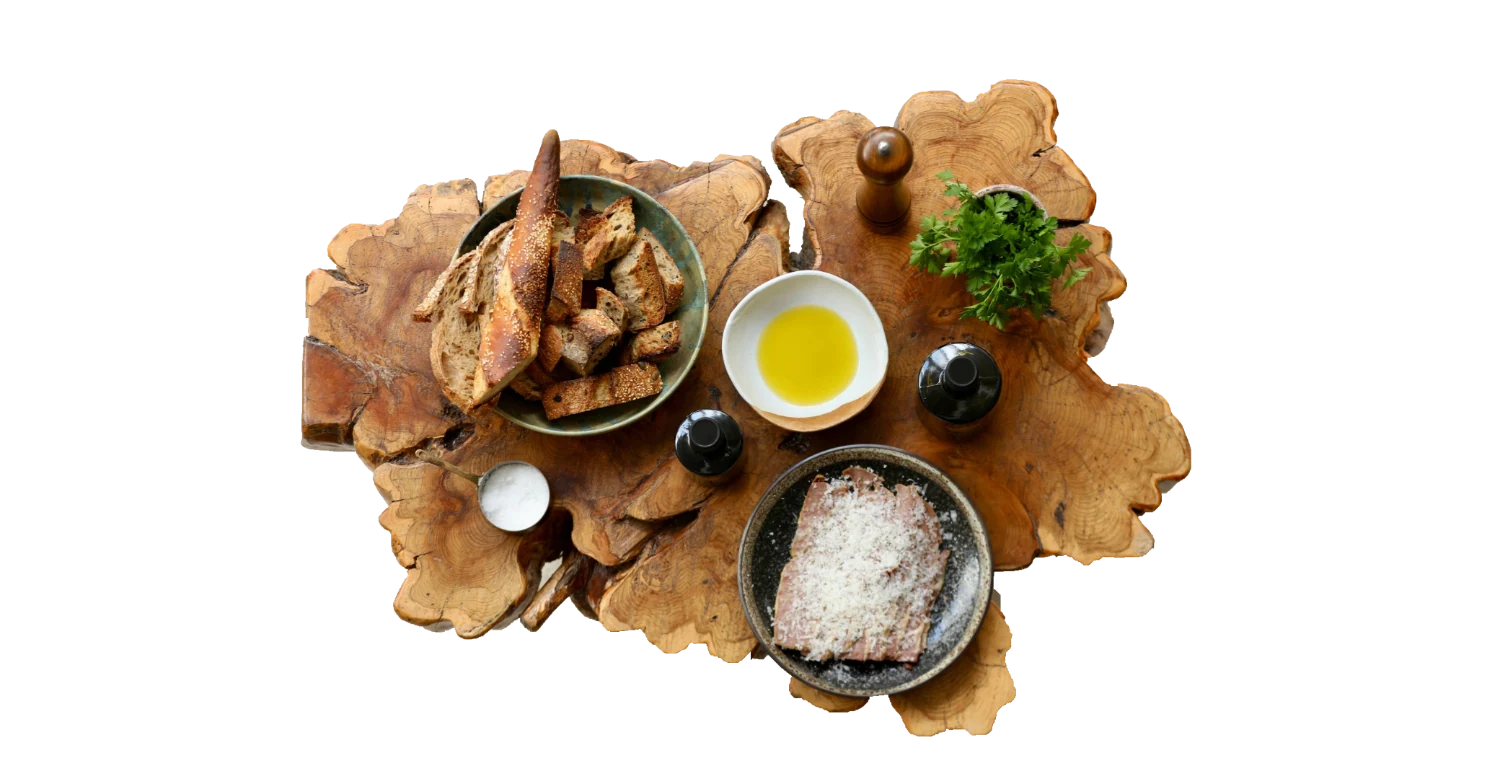 A Sicilian table — sourdough, sea salt, grated cheese, herbs and Castruriali olive oil on a live-edge board